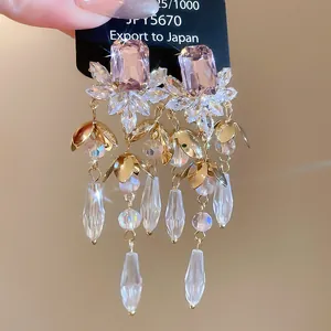 Detailed macro shot of luxury tassel earrings featuring pink crystals and clear pendants.