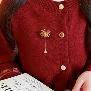 Detail shot showing an elegant firework brooch pinned on a deep red knitted cardigan