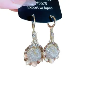 Elegant gold-tone drop earrings with sparkling rhinestones and pink stones on black card