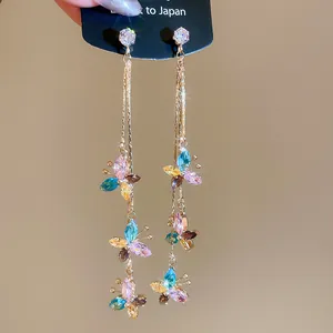Detailed view of long tassel earrings with colorful butterfly-shaped rhinestones in gold.