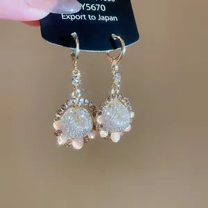 Detailed macro view of elegant gold-toned drop earrings with sparkling crystals and cat eye stones
