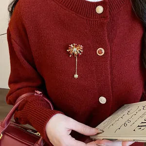 Detail of a sparkling firework flower brooch with snowflake tassel on a red cardigan