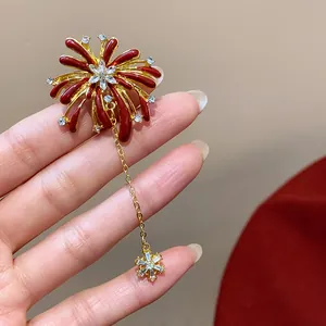 Macro view of a red and gold firework flower brooch with dangling star charm
