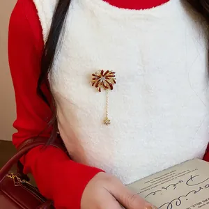 Detailed view of an exquisite red enamel firework brooch pinned on a white fuzzy sweater.