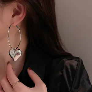 Minimalist silver needle heart hoop earrings with oversized design worn by model