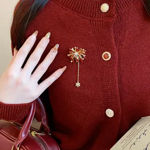 Detailed view of crystal firework brooch with snowflake dangle on red cardigan