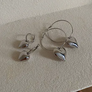 Silver heart-shaped hoop earrings in minimalist ins style on stone background