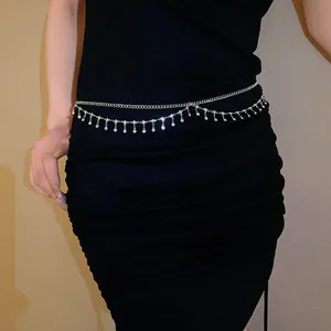 Chaîne de taille argentée à double couche avec franges en strass sur robe noire.
