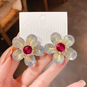 Primer plano de elegantes pendientes de flores con centro de cristal rojo y pétalos de cristal.