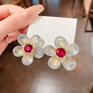 Primer plano detallado de pendientes de flor con gema roja brillante y pétalos de tipo ópalo