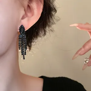 Detailaufnahme eleganter schwarzer Strass-Quastenohrringe für das Abendkleid