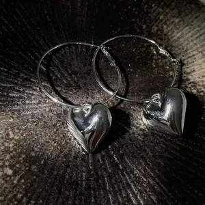 Detailed close-up view of elegant silver hoop earrings with polished heart charms