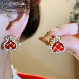 Close-up of elegant red fortune bag stud earrings with pearls and gold plating finish