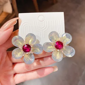 Primer plano de elegantes pendientes de flor con pétalos claros y centros magenta.