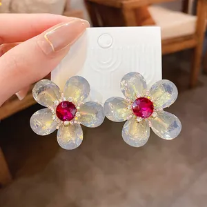 Primer plano de pendientes de flores iridiscentes con gema central rosa brillante