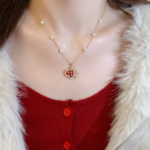 Detail shot of a festive gold lucky bag pendant necklace with pearls and zircons