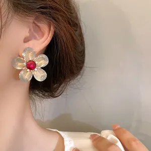 Primer plano de un elegante pendiente de flor con cristal rojo en la modelo