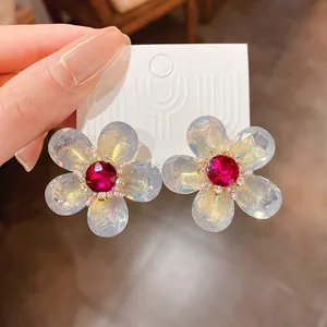 Primer plano de pendientes de flores con cristales rojos sobre cartón.