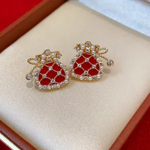 Close-up of gold-plated lucky bag stud earrings with pearls and red enamel