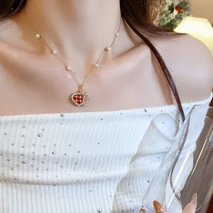 Close-up of a gold-plated pearl necklace with a red zircon-studded fortune bag pendant.