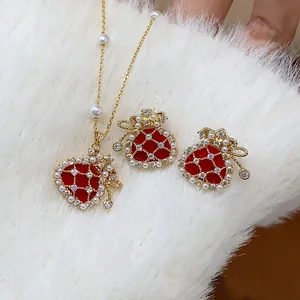 Close-up detail of a red lucky bag necklace and earrings set with zircons and pearls.