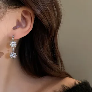 Dettaglio di eleganti orecchini pendenti a fiore in cristallo indossati da una modella