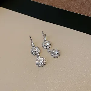 Dettaglio di eleganti orecchini pendenti a fiore in argento con strass scintillanti