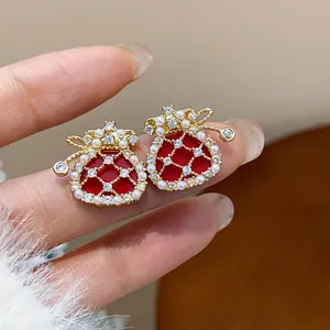 Detailed close-up of red lucky bag earrings with gold plating, pearls, and zircons.