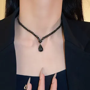 Detail der schwarzen Strass-Halskette mit Tropfenanhänger, getragen zum schwarzen Blazer