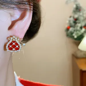 Detail shot of a gold-plated lucky bag earring featuring red enamel, zircon, and pearls.