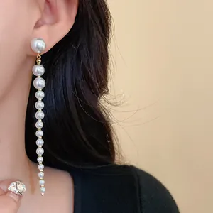 Close-up detail of elegant vintage long pearl tassel drop earring worn by an Asian model