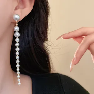 Close-up of elegant long tassel earrings with graduated white pearls on a model's ear