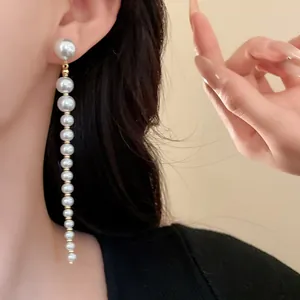 Close-up of elegant French vintage long tassel earrings with graduated pearls on model.