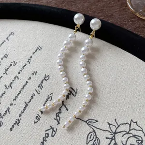 Macro detail of French retro long pearl tassel earrings resting on textured vintage fabric