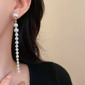 Macro view of elegant long pearl tassel earrings with silver needle earring posts