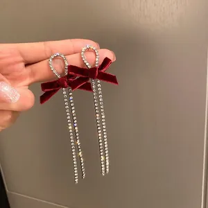 Close-up of elegant red velvet bow earrings with long sparkling rhinestone tassels