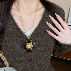 Detailed view of an amber resin flower pendant with golden embossed center on a sweater