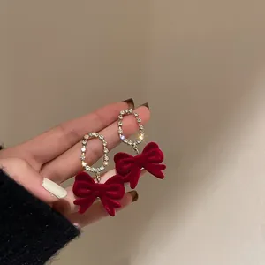 Close-up detail of vintage red velvet bow earrings featuring sparkling rhinestone hoops