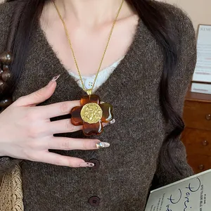 Detailed macro view of retro amber resin flower pendant necklace on brown cardigan