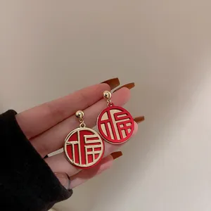 Close-up of red and gold round earrings featuring the Chinese Fu character design