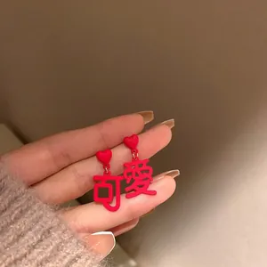 Macro detail of red heart earrings with Chinese characters on a warm lifestyle background