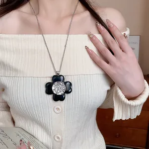 Close-up of vintage black flower pendant necklace with silver medallion on model