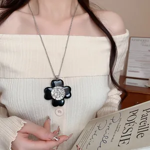 Close-up of vintage black four-petal flower pendant necklace on long silver chain