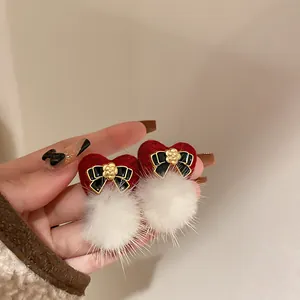 Close-up of vintage red heart earrings with black bows and white fluffy fur pom-poms