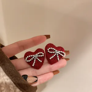 Macro view of red heart earrings with pearl bow and sparkling rhinestone detail