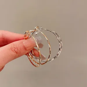 Minimalist twisted metal hoop earrings set in gold and silver finish with silver pins