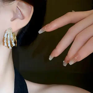 Detailaufnahme eleganter goldener dreilagiger Ohrringe mit trapezförmigen Kristallen
