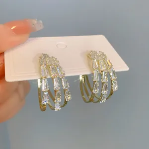 Detailansicht von dreilagigen Goldcreolen mit funkelnden Zirkonia-Kristallen im Baguetteschliff.