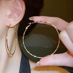 Elegant hammered gold-colored large hoop earrings with silver needles for stylish women