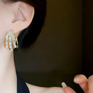 Detailansicht von dreilagigen Goldreifenohrringen mit Baguette-Kristallen am Modell